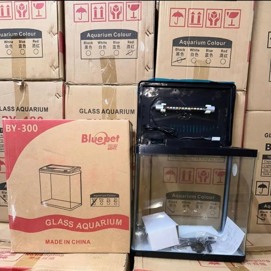 Glass aquarium with Bluepet branding on a background of stacked cardboard boxes.